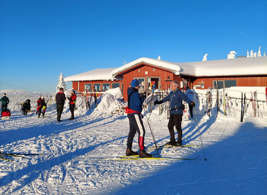 Rød hytte med skiløpere foran