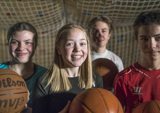 To jenter og to gutter som holder basketballer foran et håndballmål