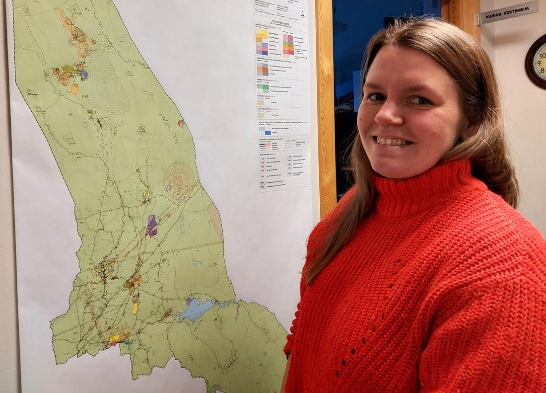 dame i rød genser som står foran arealkart over kommunen